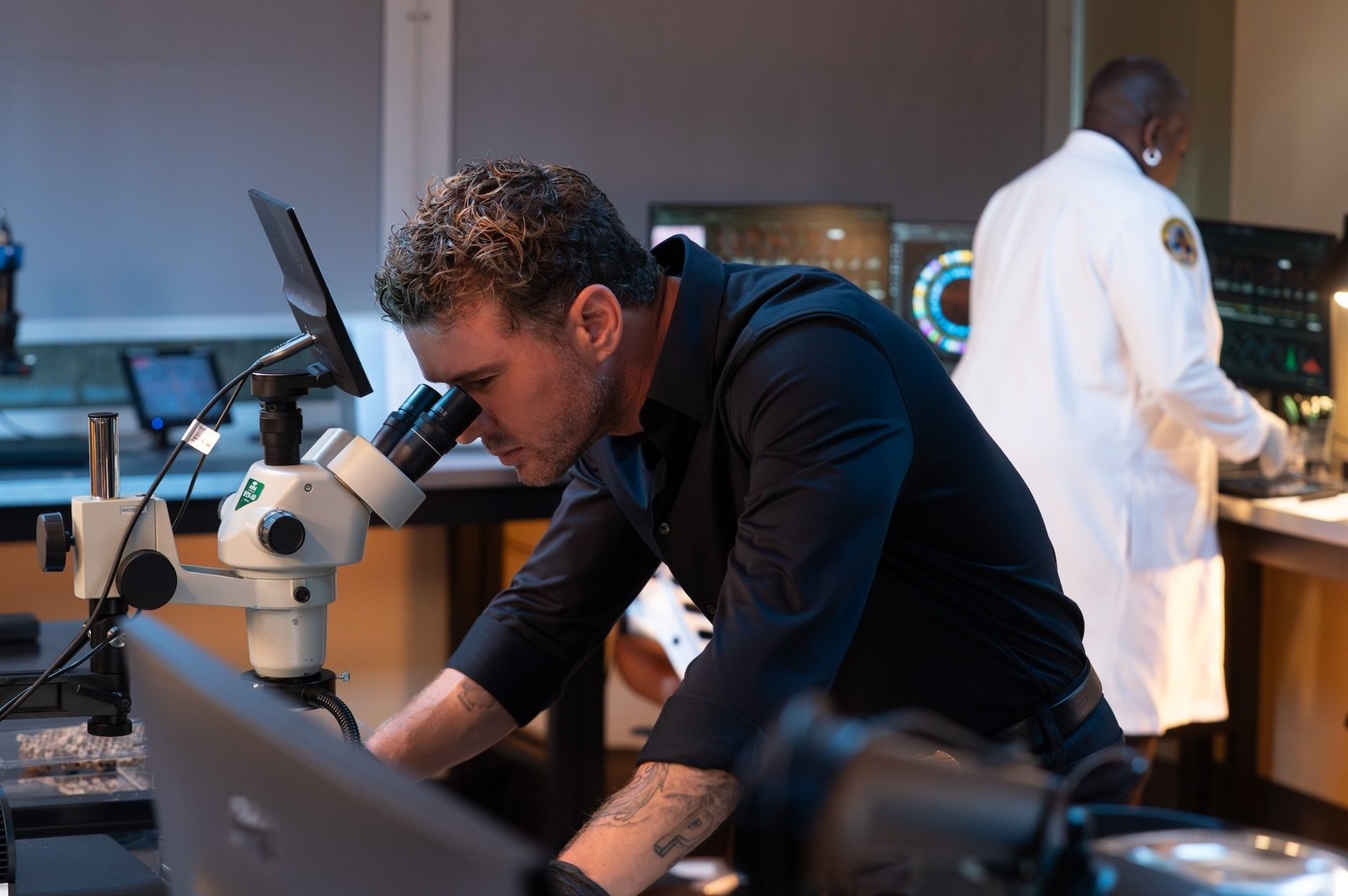 9-1-1: Nashville 2. sezon ABC resmi karesinden laboratuvarda mikroskoba bakan Rogue Kelly rolündeki Ryan Phillippe