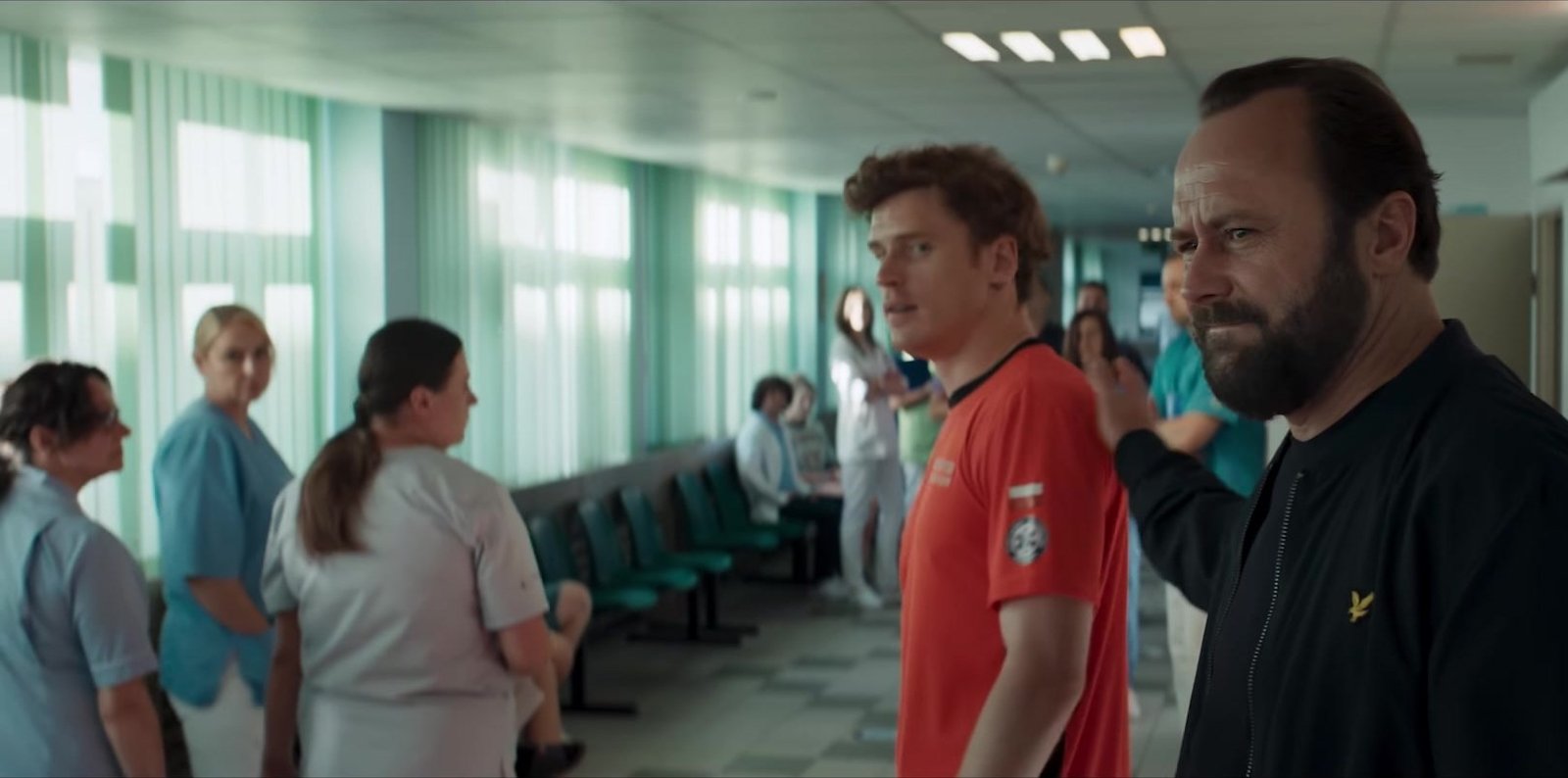 Anaesthesia (Znieczulenie) 4 Kasım’da Netflix’te: Leszek Lichota kuralları yıkan beyin cerrahı rolünde 2026 – 2 Anaesthesia fragmanından hemşirelerin beklediği hastane koridorunda kırmızı tişörtlü bir gençle konuşan sakallı doktor