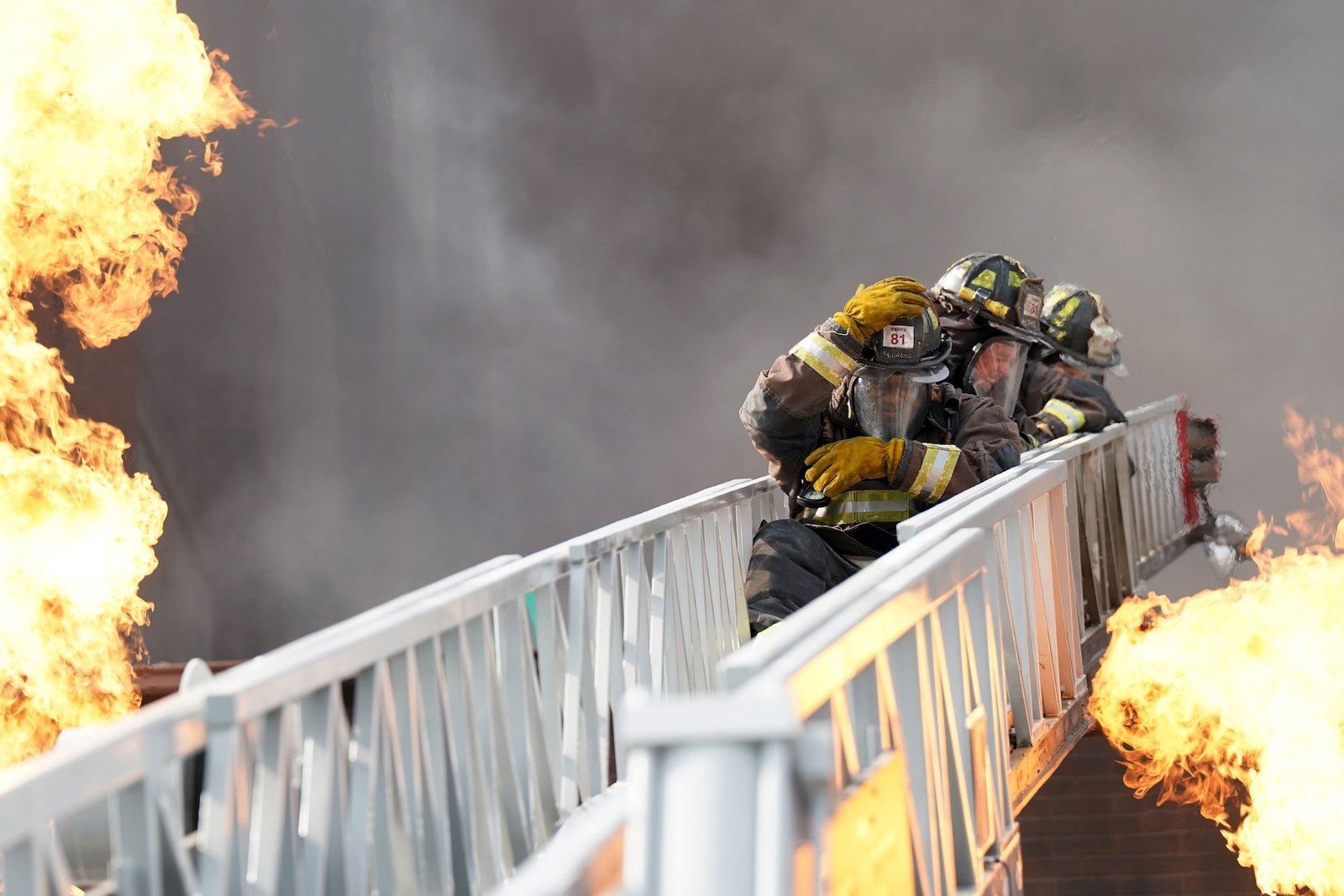 Chicago Fire 15. sezon NBC resmi karesinden Leroy Williams III ve David Eigenberg alevler arasında merdivende
