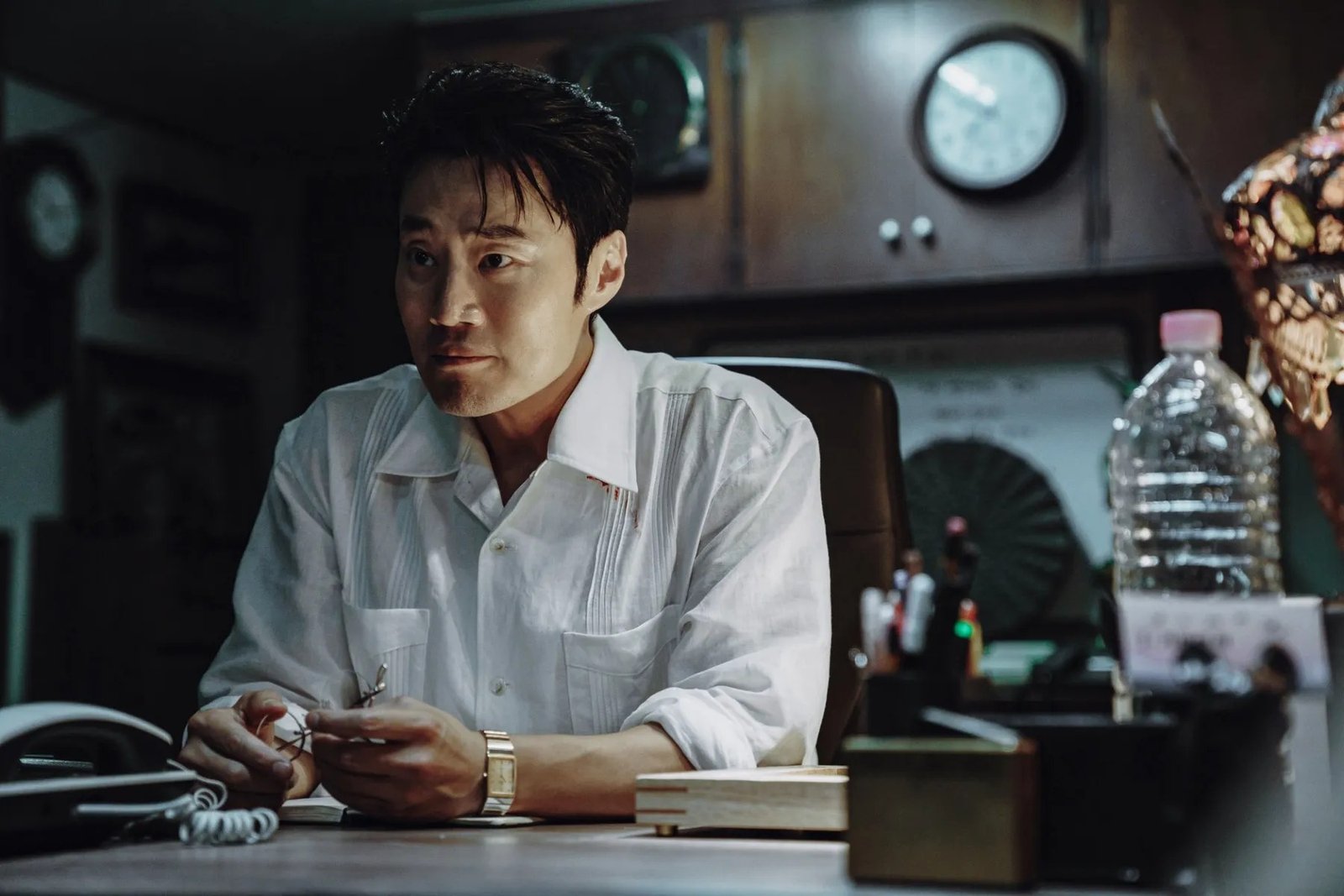 Dead-End Job 30 Ekim’de Netflix’te: Lee Jae-wook’lu Kore dizisinde ölümcül yarı zamanlı iş 2026 – 1 Dead-End Job Netflix resmi karesinden duvar saatinin altında masasında oturan Spider Staffing Agency patronu rolündeki Lee Hee-jun