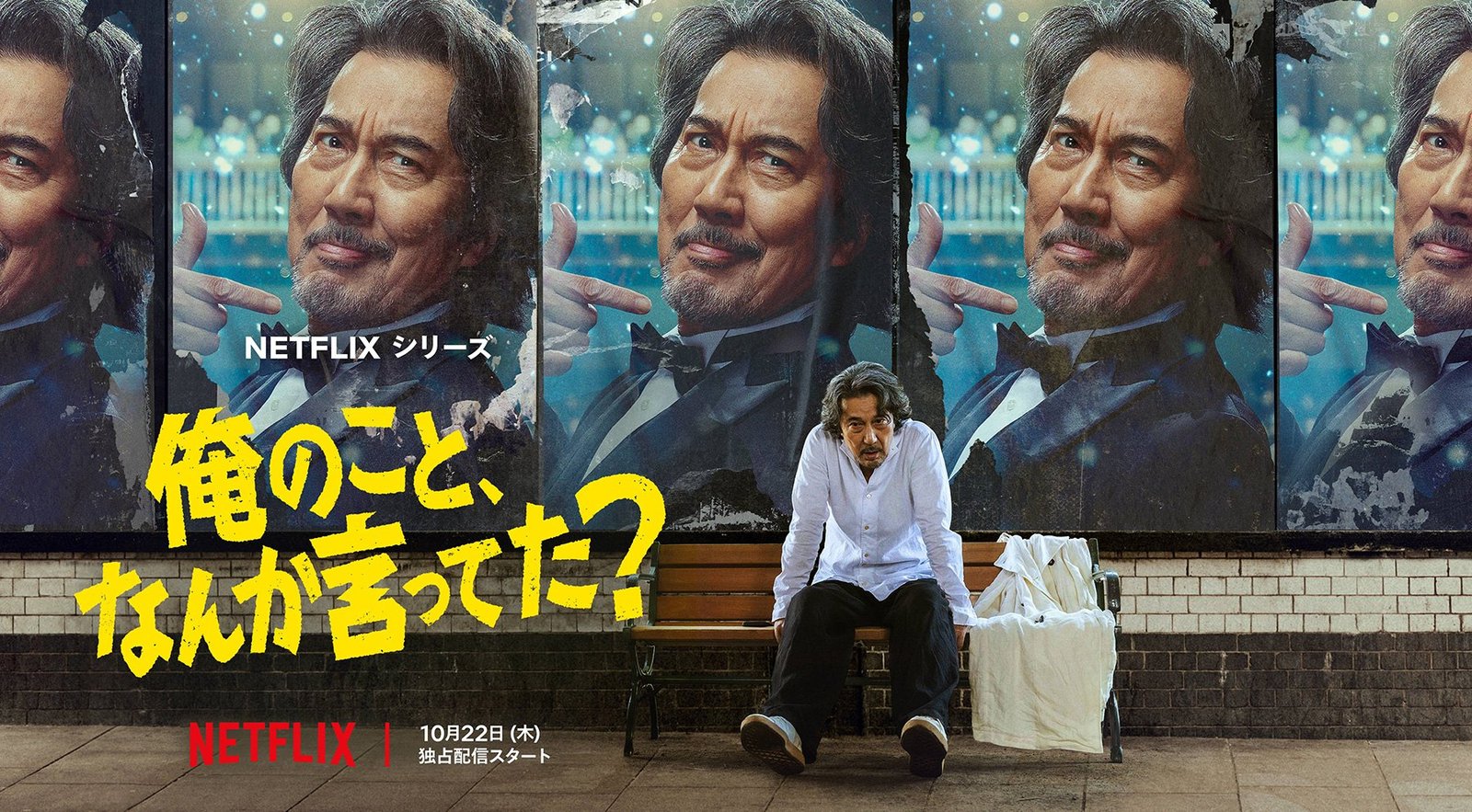 Did Someone Happen to Mention Me? Netflix resmi tanıtım görseli, afişlerin önünde bankta oturan Koji Yakusho
