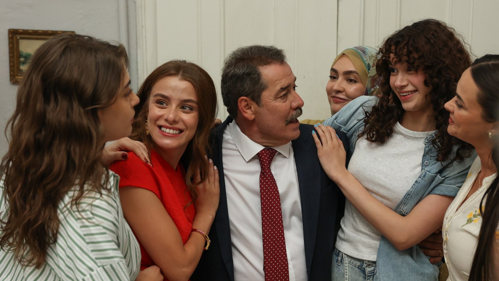 Evlilik Güzeldir TRT 1 resmi karesinden kızlarıyla çevrili, kırmızı kravatlı Mesut Bahtiyar rolündeki Fikret Kuşkan