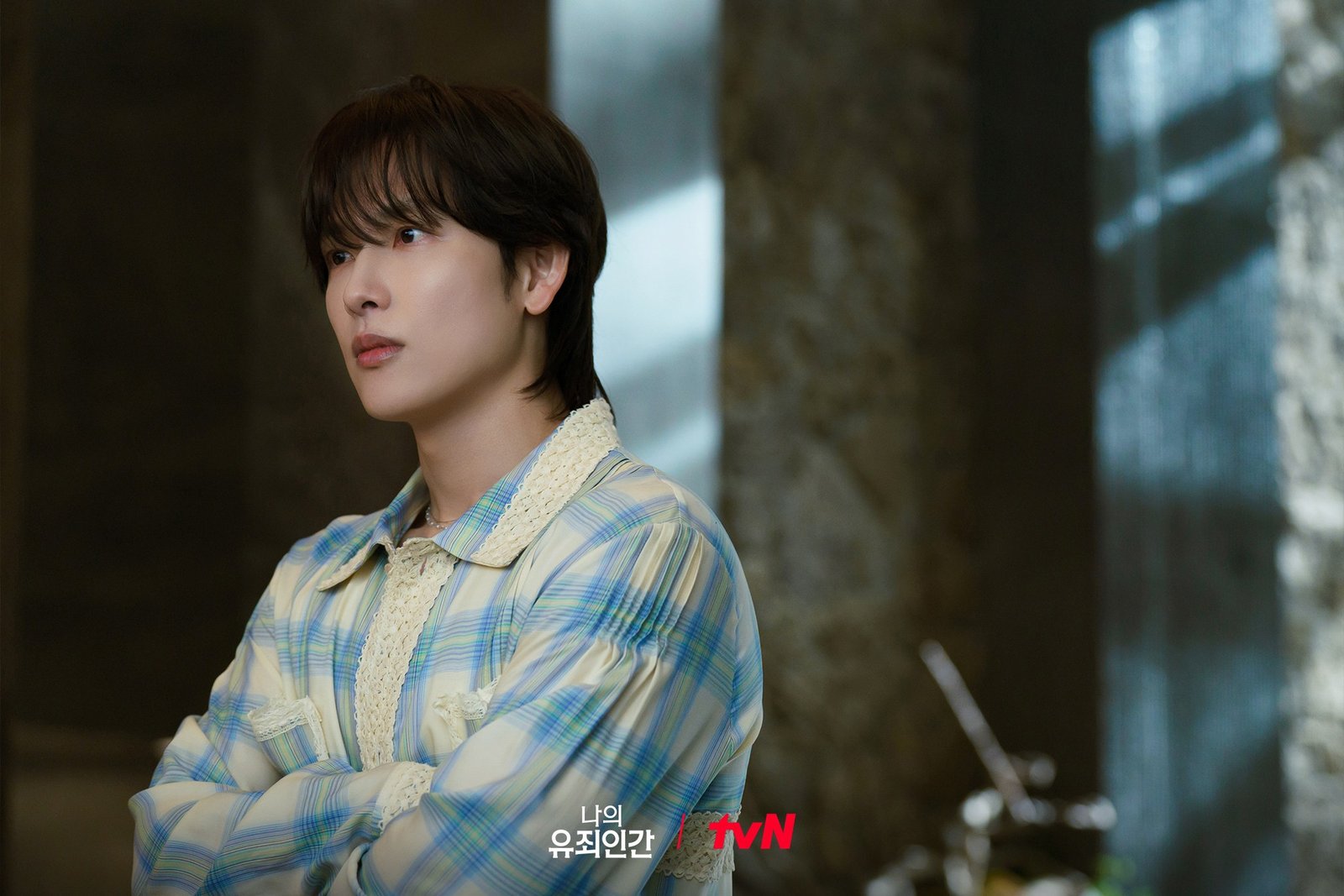 Love in Disguise tvN resmi karesinden ekose gömleğiyle kollarını kavuşturup yan tarafa bakan Yoon Yi-jun rolündeki Yim Si-wan