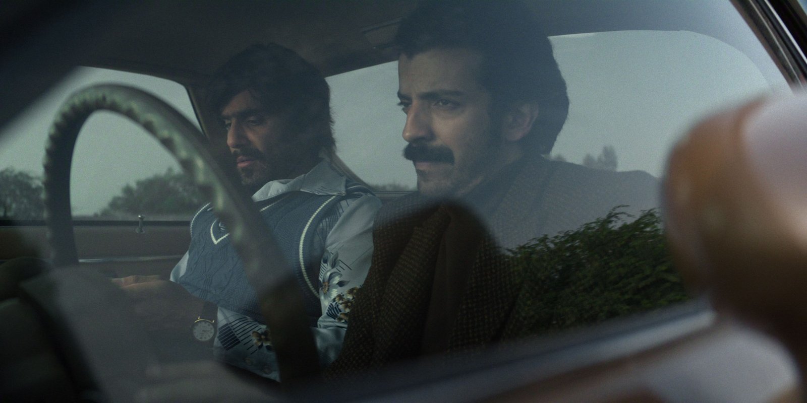Obsess Netflix resmi karesinden eski model bir otomobilin içinde oturan bıyıklı iki adam