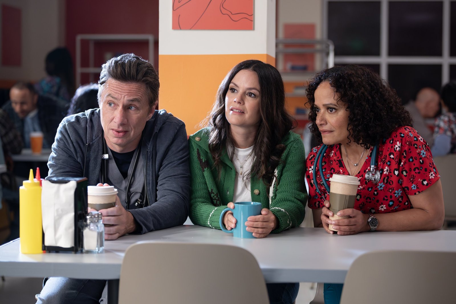 Scrubs 2. sezon ABC resmi karesinden hastane kafeteryasında oturan Zach Braff, Rachel Bilson ve Judy Reyes