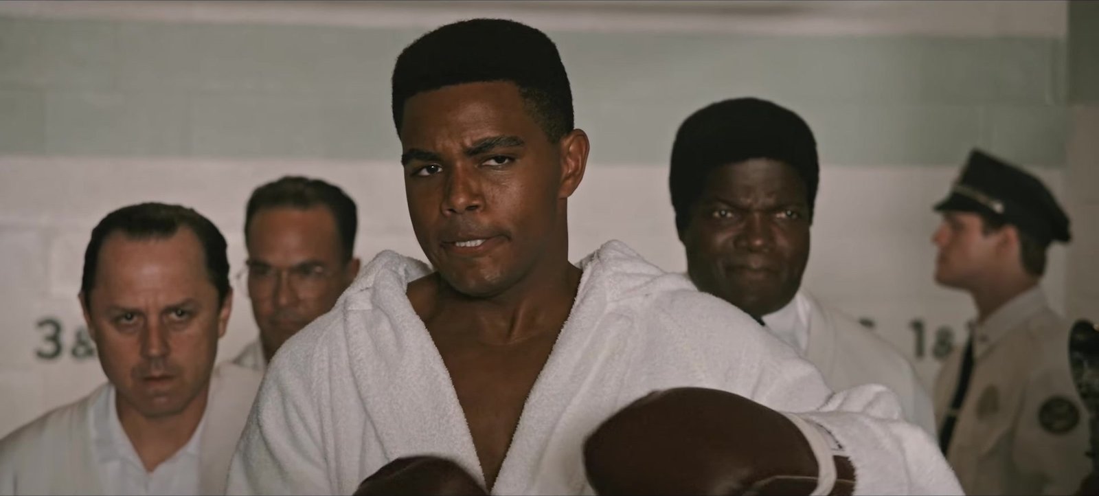The Greatest fragmanından beyaz bornozuyla çevresindeki ekiple birlikte kameraya bakan Cassius Clay rolündeki Jaalen Best